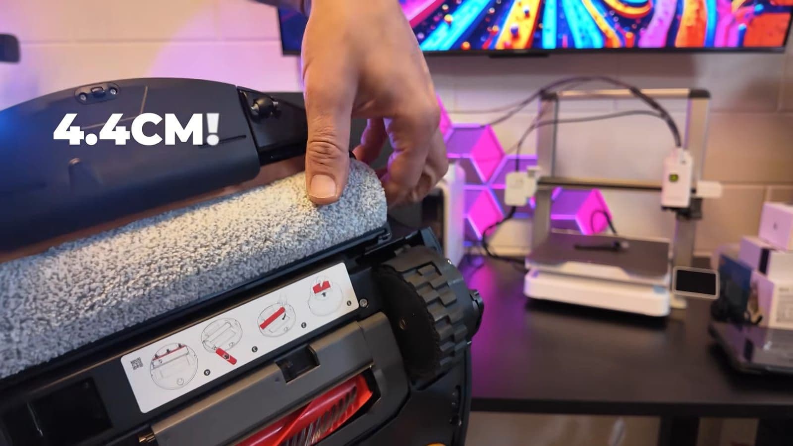 Hand trekt de rolmop van de robotstofzuiger zijwaarts uit, met in beeld de tekst 4.4CM