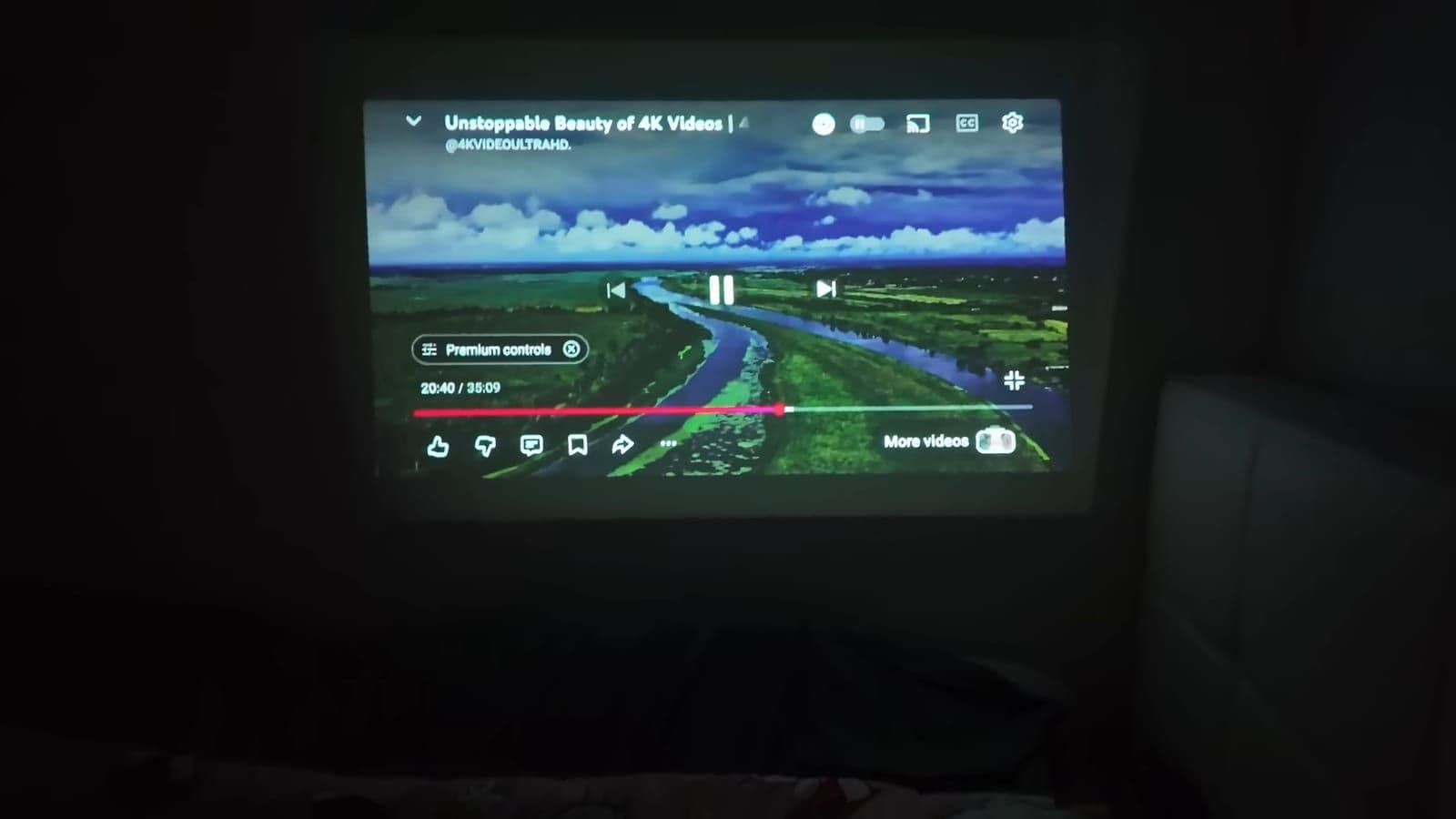 A YouTube video playing on a wall in a dark room through the built-in projector