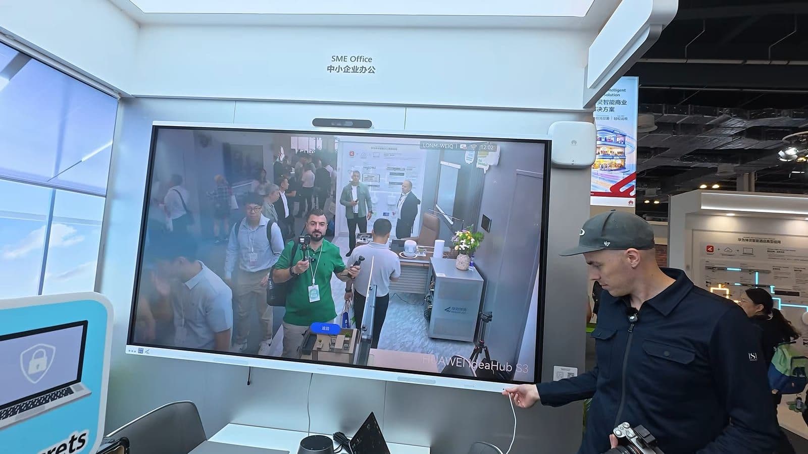 Huawei IdeaHub S3 scherm in een SME Office opstelling met live camerabeeld van bezoekers op de beursvloer